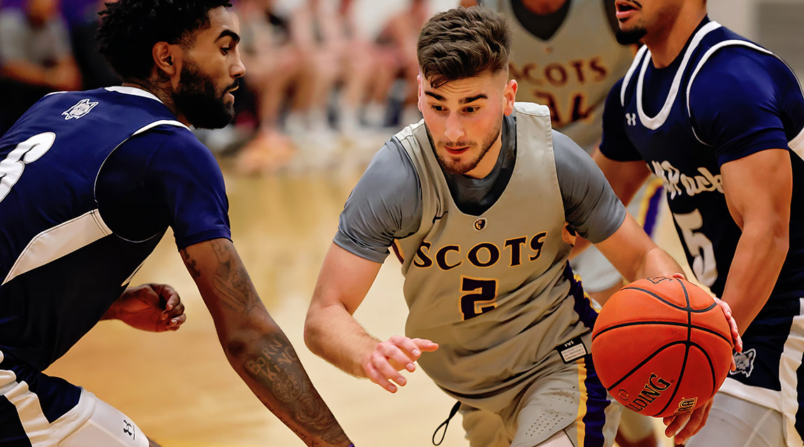 Nick Vuckovic (#2) dribbling past two defenders in blue uniforms during an intense game against Madison College.